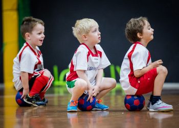 Boys sitting on soccer balls in kids soccer class